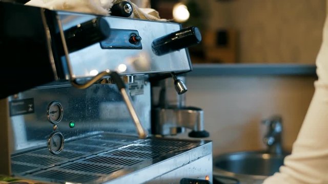 The girl fills a cup with hot water from the coffee machine. Hands close up. Hand girl baristas dub coffee from holder coffee machines