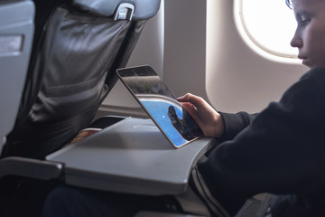 Caucasian boy fasten seat belt and using tablet pc during air flight.  Safety travel with kid....