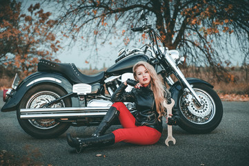 Plakat Young beautiful caucasian woman posing with motorcycle on the road.
