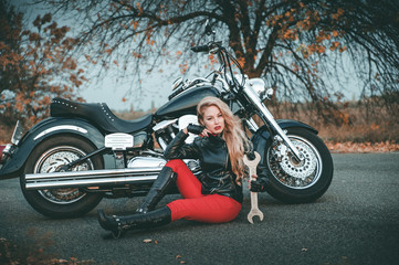 Obraz na płótnie Canvas Young beautiful caucasian woman posing with motorcycle on the road.
