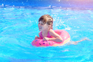 Fototapeta na wymiar Cute little girl with inflatable donut ring in swimming pool on