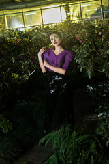 Charming girl in leather pants looking at camera in orangery