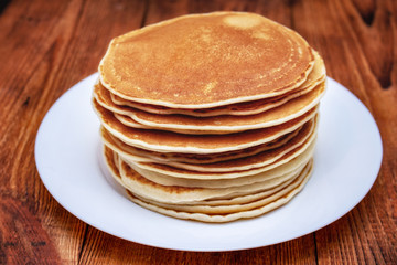 stack of pancakes on a white plate on a dark brown background