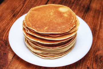 stack of pancakes on a white plate on a dark brown background