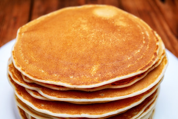 stack of pancakes on a white plate on a dark brown background