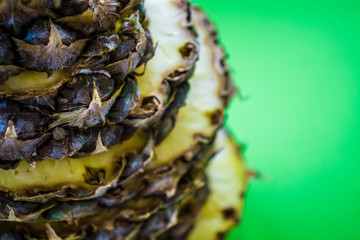 The fresh pineapple cut on round pieces. Tropical, exotic fruit on a green background. Summer. Bright colors.