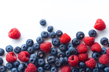 Raspberries and blueberries isolated on white background with copy space