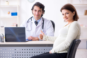 Obraz premium Old pregnant woman visiting young male doctor