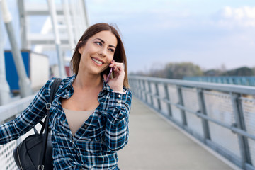 Beautiful young girl on the bridge talking on her phone