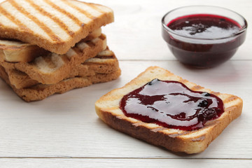 toasts with jam. fried crispy toasts with red jam on a white wooden table.
