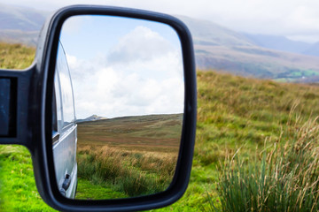 Landscape reflecting in car mirror.