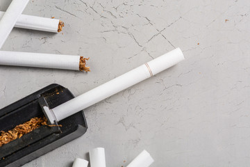 making cigarettes,on a gray background, tobacco and a tool for manufacturing cigarettes, smuggling cigarettes, top view, copy paste space