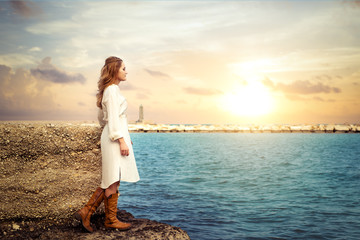 Schöne junge Frau in weißem Sommerkleid posiert am Meer. Fashion Sommer Konzept. Helle Farben. 