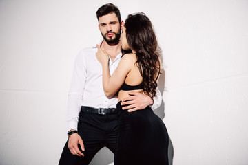 pretty woman in black bra touching handsome bearded man on white
