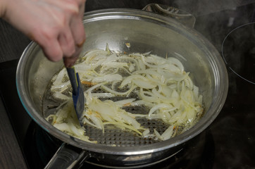Cook fries onion in the pan on sunflower oil