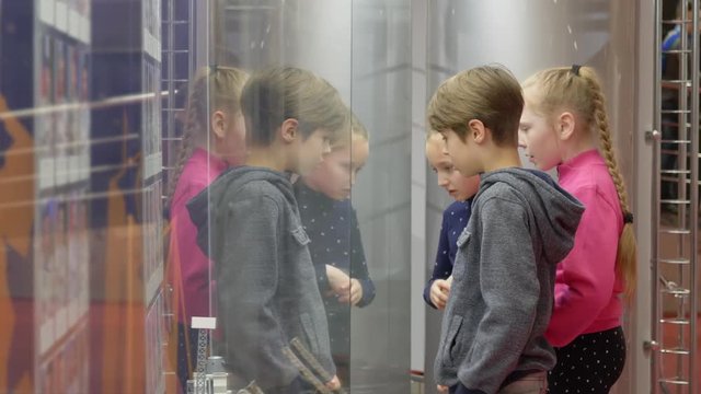 Group teenager looking glass showcase on exhibition or museum glass window. Teenagers reflecting at glass mirror efect. Involvement and interest