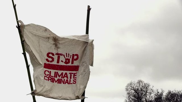 a banner waving in the wind; stop climate criminals. a protest against global warming and for a change of the climate law