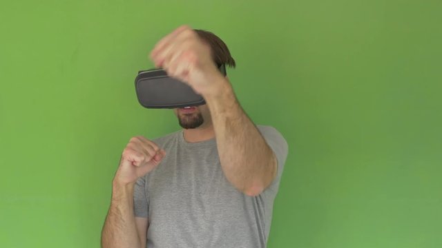 Medium shot of Man with VR Goggles standing and virtual boxing on green screen