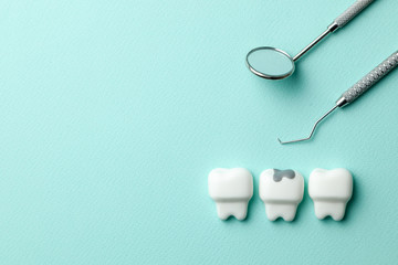 Healthy white teeth and tooth with caries on green mint background  and dentist tools mirror, hook....