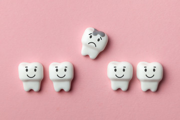 Healthy white teeth are smiling and removing tooth with caries is sad against pink backgroundhook.