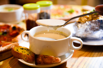Bowl on a table with mushroom soup and a spoon hovering above