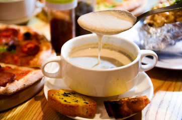 Bowl on a table with mushroom soup and a spoon hovering above