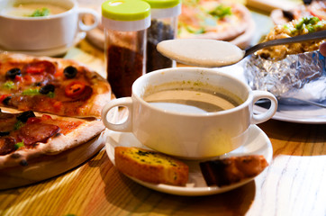 Bowl on a table with mushroom soup and a spoon hovering above