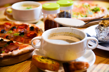 Bowl on a table with mushroom soup and a spoon hovering above