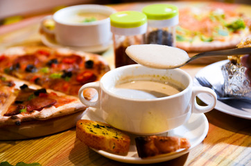 Bowl on a table with mushroom soup and a spoon hovering above