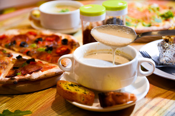 Bowl on a table with mushroom soup and a spoon hovering above