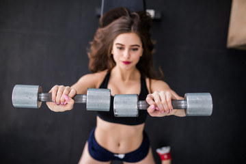 Gorgeous brunette woman lifting some weights and working on her biceps in a gym