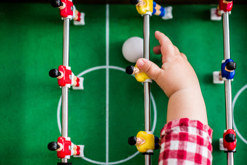A child reaching for the football in a table football game