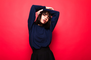 Positive attractive woman wears casual sweater,isolated against red background