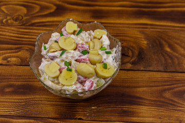 Potato salad with marinated mushrooms, sausage, onion and mayonnaise on wooden table