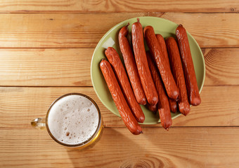 A small glass of beer and smoked sausage on the table.