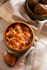 sauerkraut with boiled potatoes in earthenware on a light background