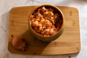 sauerkraut on a cutting board in pottery and light background