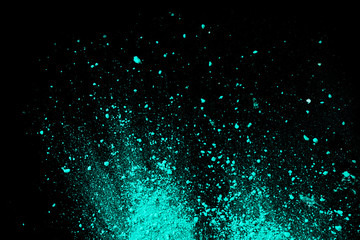 A splatter of green blue colored pigment powder on black background.