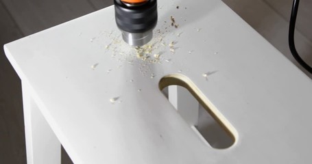 Closeup of a drill bit drilling a hole in a wooden plank