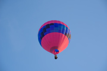 Red and blue hot air balloon seen from below against blue sky