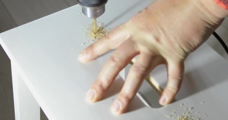 Closeup of a drill bit drilling a hole in a wooden plank