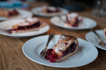Tasty cherry pie on plates, placed on wooden table