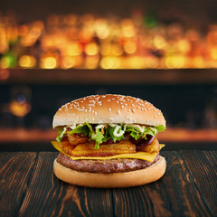 burger with fried patato and cheese at wooden tabletop with blurred bar at backdrop . Fastfood...