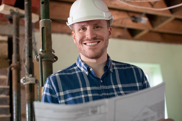 Portrait Of Architect Inside House Being Renovated Studying Plans