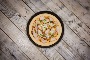Round pizza dough is in the pan. The process of cooking pizza, stacking ingredients on the dough.