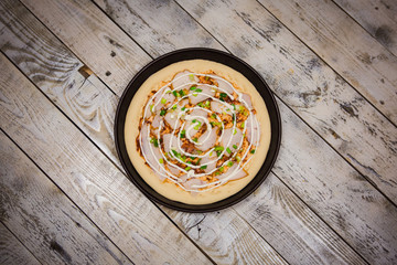 Round pizza dough is in the pan. The process of cooking pizza, stacking ingredients on the dough.