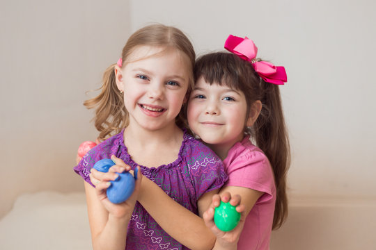 two happy cute babies sisters, twins 6-7 years old with beautiful Easter eggs in their hands hugging
