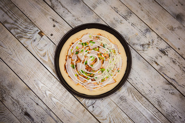 Round pizza dough is in the pan. The process of cooking pizza, stacking ingredients on the dough.