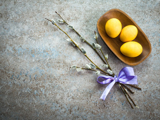 Happy Easter greeting card, copy space. Colored Easter eggs in wooden plate on the stone background. Easter concept.