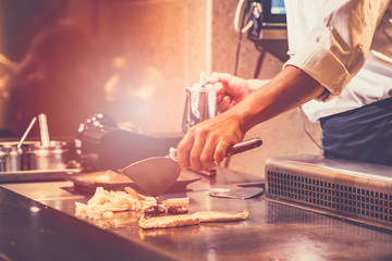The chef cooks fresh, fast food according to the orders of customers in the Japanese teppanyaki restaurant.